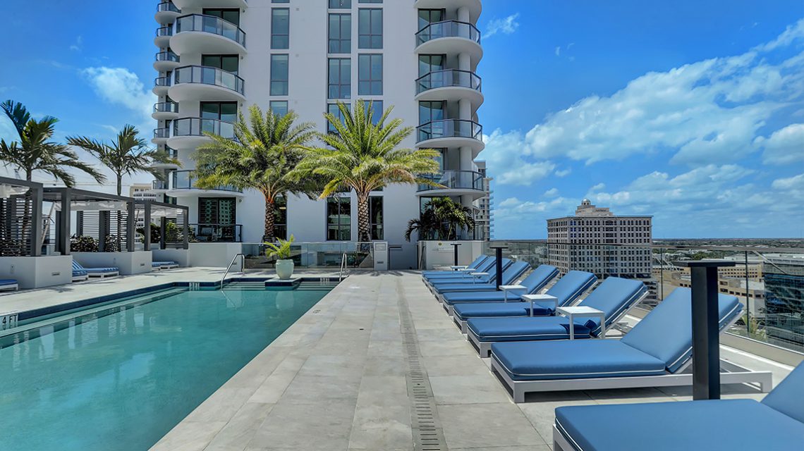 Image of pool with lounge chairs lined up on edge of pool