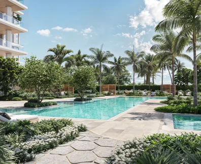 Beachfront residential pool with palm trees, landscaped gardens, lounge chairs, and modern condominium balconies beside the ocean.
