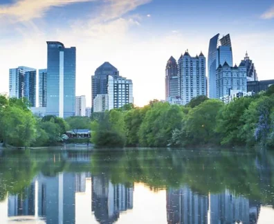 Atlanta skyline reflected in calm lake with trees and sunset sky