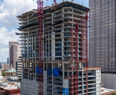 High-rise building under construction with cranes in city