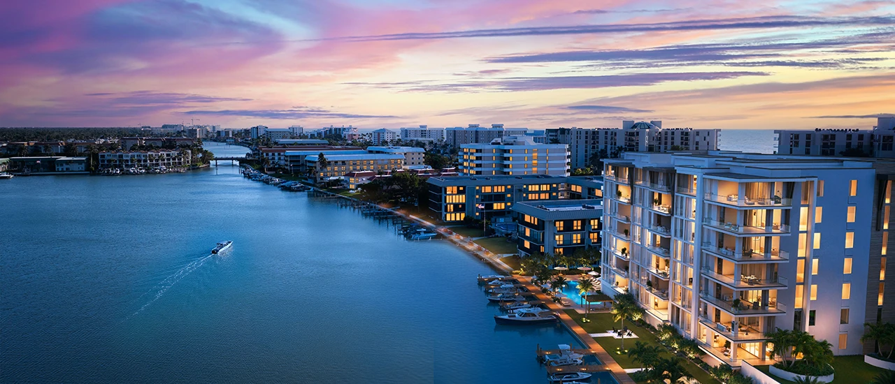 Waterfront condos and marina with boats illuminated at dusk under colorful sunset sky